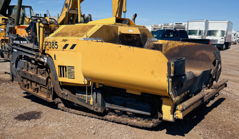 Front side view of a Weiler P385 Asphalt Paver on tracks. The paver features dual controls and an electric heated 97 to 187-inch screed. It is equipped with an onboard generator and has 14-inch track shoes with rubber pads. The paver has been used for 2,755 hours.